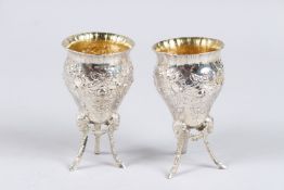 A PAIR OF VICTORIAN SILVER PEDESTAL VASES, with floral decorated embossed and chased bodies on three