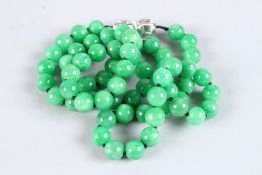 A VERY GOOD STRING OF JADE BEADS with a white gold and diamond clasp. 32ins long.