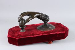 A SUPERB LARGE BRONZE HAND DOOR KNOCKER. 9.5ins long, mounted on a red velvet base.