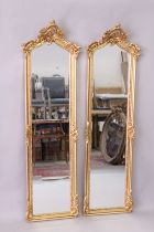 A PAIR OF DECORATIVE GILT FRAMED NARROW MIRRORS, with scroll work and flower crestings, 5ft 9in high