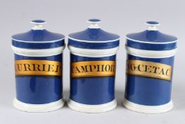 THREE BLUE APOTHECARY JARS AND COVERS. CAMPHORA, CURRIEP AND VEG:CETAC. 7.5ins high.
