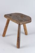 A RUSTIC THREE LEGGED STOOL.