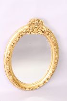 A DECORATIVE FRENCH STYLE GILT FRAMED OVAL WALL MIRROR, with floral swag cresting, 3ft high x 2ft