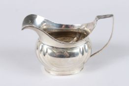 A GEORGE III CREAM JUG, with strap handle, embossed decoration to the body, London 1804, maker SD