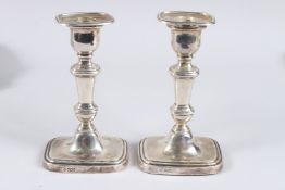 A PAIR OF SILVER CANDLESTICKS, with weighted rounded rectangular bases, Sheffield 1918, maker H E