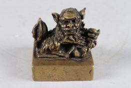 A CHINESE BRONZE SQUARE SHAPE SEAL, modelled as a Kylin and young, 3in wide.