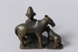 AN 18TH CENTURY INDIAN BRONZE FIGURE of a man milking a cow. 3ins long.