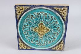 A CHINESE 'FAHUA' TYPE POTTERY TEMPLE TILE, with stylised moulded decoration, 8in x 8in.