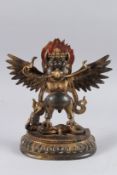 A TIBETAN GILT BRONZE STANDING BUDDHA, with arms outstretched, a snake in its mouth, 11in high.