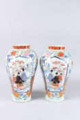 A PAIR OF JAPANESE IMARI VASES, painted with figures and flowers on two panels. 14ins high.