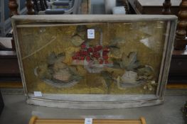 A felt work three dimensional picture depicting fruit in a bow fronted display case.