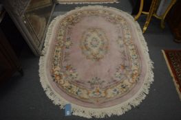 A Chinese pink ground oval shaped rug, 190cm x 130cm.
