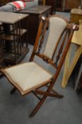 A walnut and upholstered folding chair.