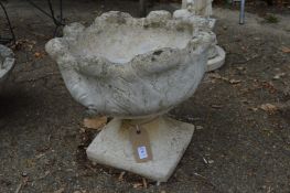 A reconstituted stone pedestal planter.