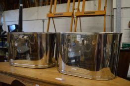 A pair of polished metal Champagne coolers.