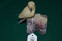 Hard stone model of a parrot mounted on an amethyst quartz base.