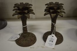 A pair of cast metal candlesticks in the form of palm trees.