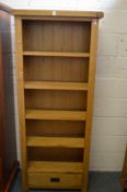 An oak open bookcase with a drawer to the base.