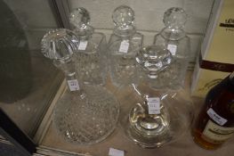 A set of three cut glass whiskey decanters (one with rim chip) together with two other decanters.
