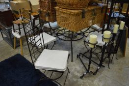 A good wrought iron and glass circular table and set of six wrought iron chairs with cushions.