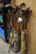 Three early golf bags containing a large quantity of clubs.