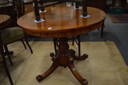 A mahogany circular tilt-top dining table.