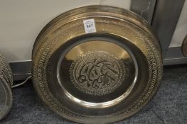 Thirteen plated circular dishes with engraved decoration.