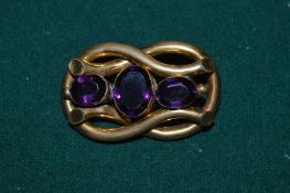 A yellow metal and amethyst brooch.