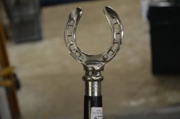 A walking stick, the handle modelled as a horseshoe.