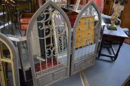 A large pair of arch shaped mirrors with painted frames and wrought iron decoration.