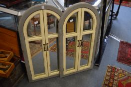 A pair of painted arch shaped window style wall mirrors.