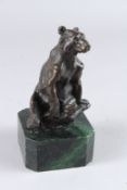 A SMALL BRONZE FIGURE OF A SEATED BEAR, on a green marble base. 6.5ins high.