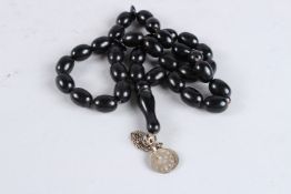 A BLACK BEAD NECKLACE with three silver coins. 24ins long.