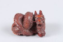 A WOODEN DRAGON NETSUKE. Signed. 2ins long.