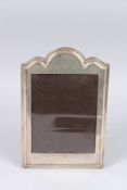 A SILVER PHOTOGRAPH FRAME with serpentine top. 11ins x 7.5ins. Birmingham 1912.