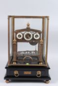 A GOOD CONGREVE ROLLING BALL CLOCK in a glass case, the base with a drawer.