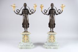A PAIR OF PATINATED AND GILDED BRONZE CLASSICAL STYLE FIGURAL TWIN BRANCH CANDELABRA, mounted on