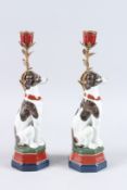 A PAIR OF SEVRES DESIGN PORCELAIN DOG CANDLESTICKS on hexagonal bases. 14ins high.