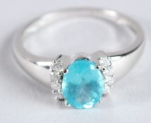 A 9CT WHITE GOLD DRESS RING set with a central blue apatite and diamonds to each side. Oval-cut