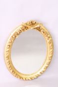 A DECORATIVE FRENCH STYLE GILT FRAMED OVAL WALL MIRROR, with ribbon and classical trophies cresting,