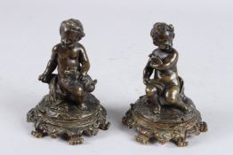 A VERY GOOD PAIR OF 18TH CENTURY BRONZE CUPIDS holding a dog, the other a bird. 5ins high.