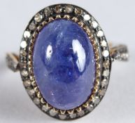 A SILVER GILT RING SET WITH A LARGE CABOCHON TANZANITE AND ROSE-CUT DIAMONDS set to the halo and