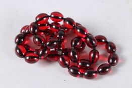 A STRING OF CHERRY AMBER BEADS. 32ins long.