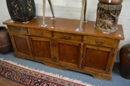 An Indonesian hardwood sideboard comprising four long drawers above four panelled cupboard doors.