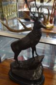 A large pair of bronze stags standing on rocky outcrops, mounted on marble bases.