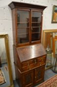 An unusual oak bureau cabinet, the upper section with pair of glazed doors above a fall-flap over an