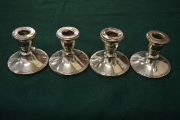 A set of four silver dwarf candlesticks.