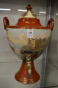 A Continental pottery urn shaped Samovar painted with a lake scene and buildings.