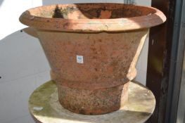 Three large terracotta planters of tapering circular form.