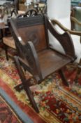 An oak Glastonbury style chair with carved decoration.